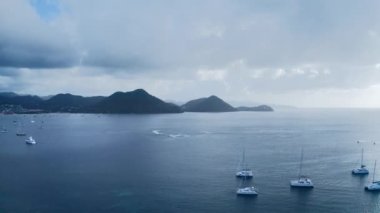 Deniz yatları arasında daireler çizen su bisikleti görüntüleri, ufuktaki dağlar, şehir ve sis (Rodney Körfezi, Saint Lucia))