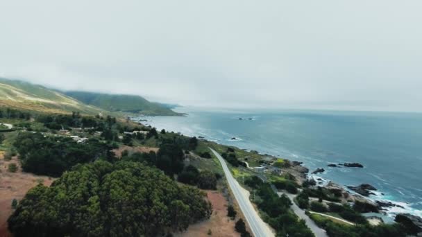 Drone, Garrapata, California, ABD 'de orman ve sis ile tepe okyanus kıyısındaki evleri ve yolları vuruyor. — Stok video