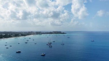 İHA kamerası, Bridgetown, Barbados yakınlarındaki sakin bir mavi denizde yatların üzerinde yükseliyor.