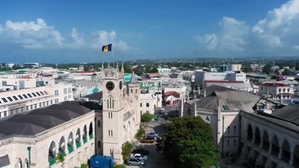 Drone beweegt over de daken van huizen van Barbados parlementsgebouw met barbadische vlag in Bridgetown — Stockvideo
