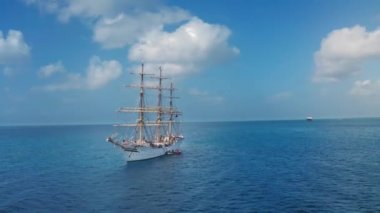 Barbados, Bridgetown yakınlarında Norveçli ve Barbadoslu bayraklarla büyük beyaz yelkenli geminin etrafında dönen hava aracı.