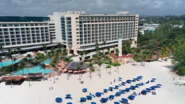 Drone se aleja del hotel resort, vegetación tropical, playa de arena blanca en Bridgetown, Barbados — Vídeo de stock