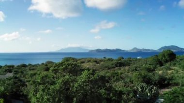 Drone kamerası sık ormanın tepelerini ve Saint Kitts ve Nevis 'teki mavi deniz ve dağları yakalar.