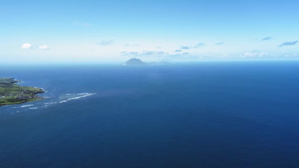 Vista aérea del mar azul, una isla con un asentamiento y sombra de una montaña en el horizonte en San Cristóbal y Nieves — Vídeos de Stock