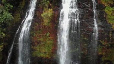 İnsansız hava aracı Opaekaa Falls, Kauai, Hawaii, ABD 'deki bir uçurumda yüksek bir şelalenin üzerinde yükseliyor.