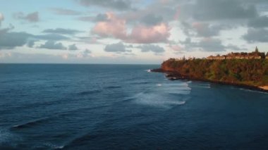 Okyanus dalgalarının havadan çekilmiş görüntüleri, Kauai, Hawaii, ABD 'de bitki örtüsü ve evler, gökkuşağı ve bulutlar.
