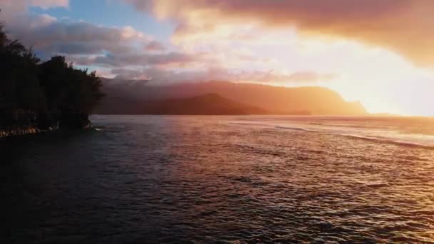 ドローンは日没時の山々の影と崖を捉え、米国ハワイ州カウアイにヤシの木があります。 — ストック動画