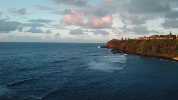 Εναέρια πλάνα των ωκεάνιων κυμάτων, ακτή με βλάστηση και σπίτια, ουράνιο τόξο και σύννεφα στο Kauai, Χαβάη, ΗΠΑ — Αρχείο Βίντεο