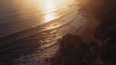 El Matador Beach, Malibu, Califronia, ABD 'de gün batımında plajın ve köpük dalgalarının hava görüntüleri.