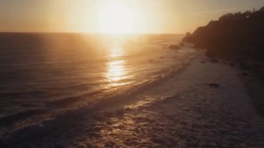 El Matador Beach, Malibu, Califronia, ABD 'de alacakaranlıkta güneş dalgalı okyanus yüzeyinin insansız hava aracı görüntüleri.
