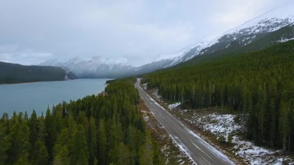Drone strzela wiosenną drogą w pobliżu zbiornika Spray Lakes otoczony gęstym zielonym lasem w Alberta, Kanada — Wideo stockowe