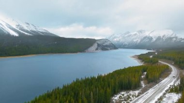 Kanada, Alberta 'daki Sprey Gölleri Barajı kıyısındaki karlı dağların etkileyici yamaçlarının videosu.