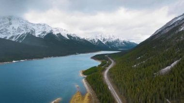 Dağ yamaçlarındaki ormanı ve Kanada 'daki Alberta Barajı yakınlarındaki bir yolu gösteren hava videosu.