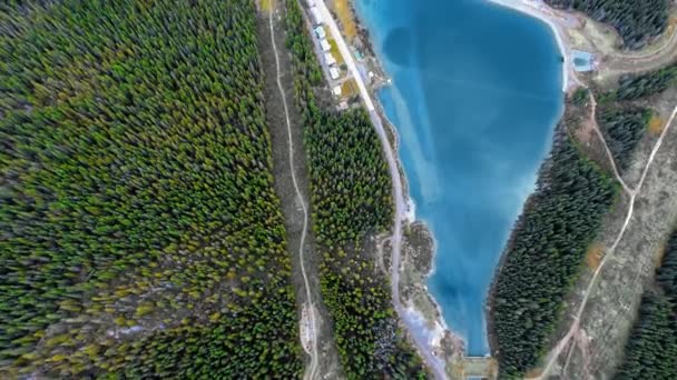 캐나다 앨버타주에 있는 울창 한 숲과 오솔길에 둘러 싸여 있는 매끈 한 푸른 호수의 드론 영상 — 비디오