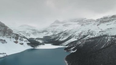 Kanada Alberta 'daki Bow Lake yakınlarındaki karanlık ormanlık tepelerin ve karlı kayaların insansız hava aracı görüntüleri.
