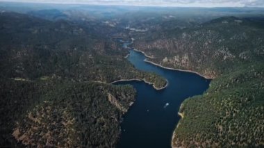 Pactola Gölü 'nün beyaz teknesi ve Wyoming, ABD' deki ağaçlık tepeleriyle kuşların gözü önünde.