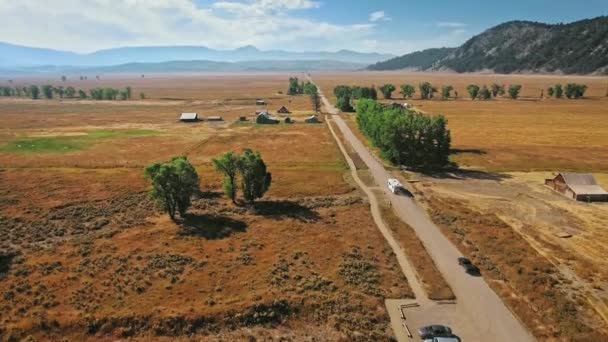 Drone stijgt op over de weg en de eindeloze gouden steppe bij Mormon Row, Wyoming, USA — Stockvideo