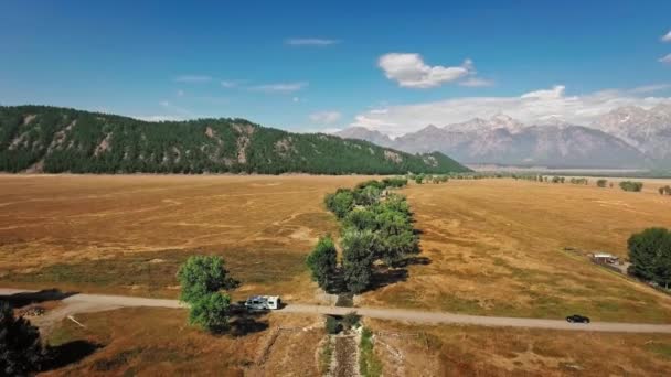Luchtbeelden tonen een eenzame trailer die over de gouden prairie rijdt in Mormon Row, Wyoming, USA — Stockvideo
