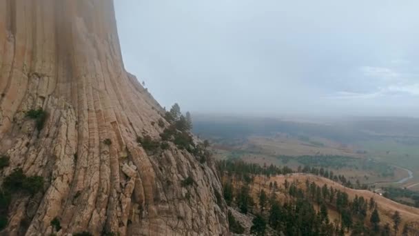 Drönare kamera flyger över en ändlös dal nära en brant klippa av Devils Tower, Wyoming, USA — Stockvideo