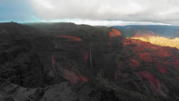 Légi felvétel Waipoo Falls-ról, amint a Waimea Canyon, Kauai, Hawaii sötét sziklái közé rohan. — Stock videók