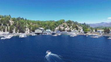 Arrowhead Gölü, Kaliforniya, ABD 'deki ağaçlık bir dağın yakınındaki tekneye ve iskeleye yaklaşan hava aracı.