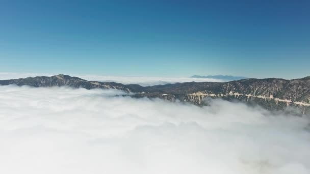 Panorama aéreo de drones de picos de montanhas arborizadas salientes acima de nuvens brancas fofas perto de Big Bear Lake, Califórnia, EUA — Vídeo de Stock