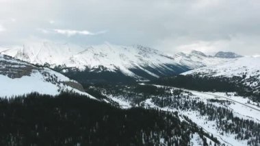 Kanada Alberta 'da kış ormanlarının ve karla kaplı kayalık dağların havadan manzarası