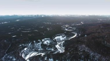 Kanada Alberta 'da yoğun bir kara ormanla kaplı dağlardaki donmuş Tetsa Nehri' nin kuş bakışı görüntüsü.