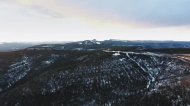 İnsansız hava aracı Kanada, Alberta 'da karlı bir dağ manzarasını, sıkıcı ormanları çevreleyip filme alıyor.