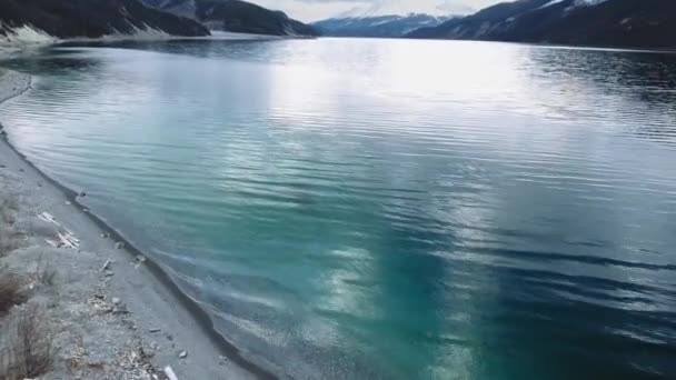 カナダのアルバータ州の透明なMuncho Lakeの銀行を覆う柔らかい波をドローンが撃つ — ストック動画