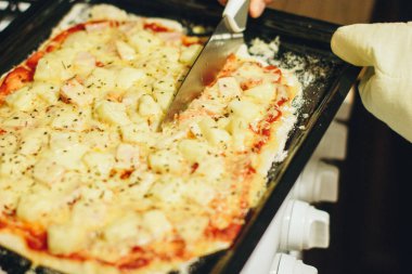 Ev yapımı pizzayı bıçakla kesmek.