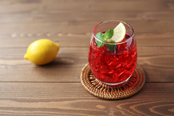 木製のテーブルの上に隔離されたレモンクローズアップと冷たい紅茶の赤い飲み物のグラス — ストック写真