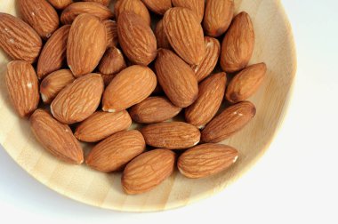 Beyaz arka planda izole ahşap plaka üzerinde badem fıstığı