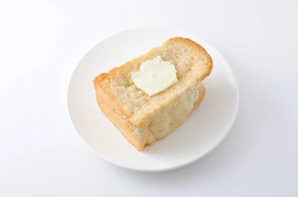Pão com manteiga torrada francesa em um prato no fundo branco — Fotografia de Stock