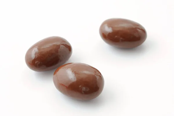 3 amandelen bedekt met chocolade op een witte achtergrond — Stockfoto