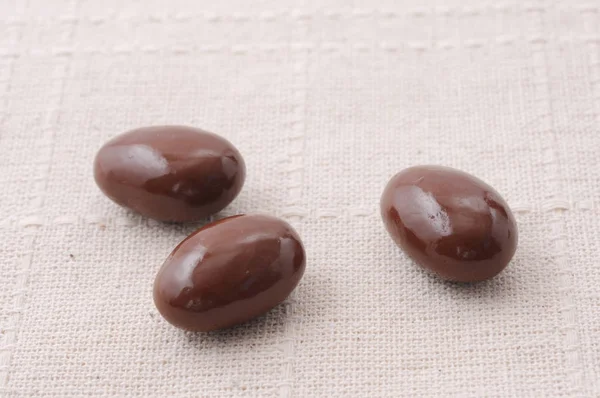 3 amêndoas cobertas de chocolate na toalha de mesa — Fotografia de Stock