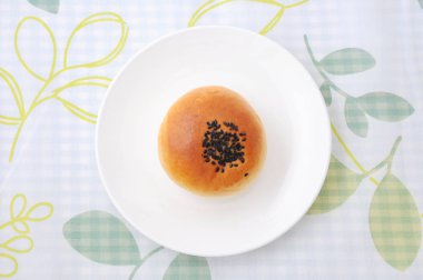 masa örtüsü üzerinde tabakta susam ile yuvarlak ekmek