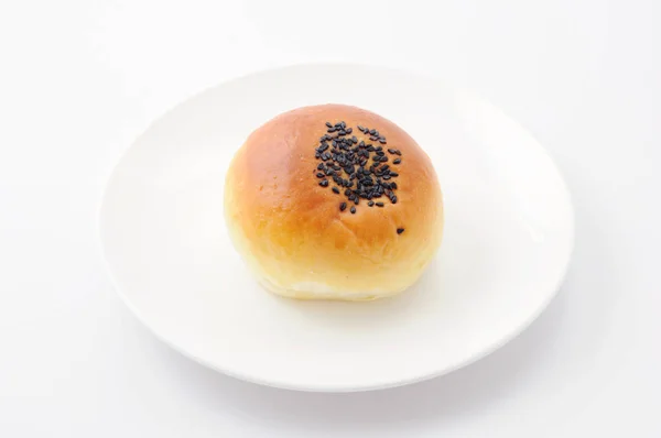Pão redondo com gergelim na placa no fundo branco — Fotografia de Stock