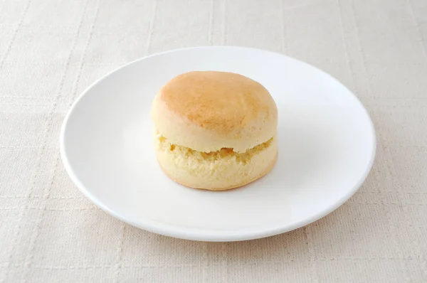 Plain scone biscuit on a plate on tablecloth — Stock Photo, Image