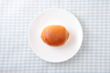 masa örtüsü üzerinde bir tabak üzerinde tereyağı ekmek rulo