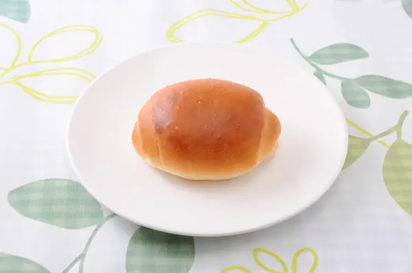 Rollo de pan de mantequilla en un plato en mantel —  Fotos de Stock
