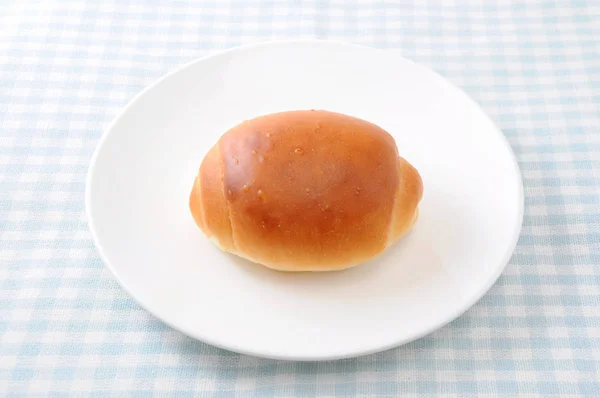 Masa örtüsü üzerinde bir tabak üzerinde tereyağı ekmek rulo — Stok fotoğraf