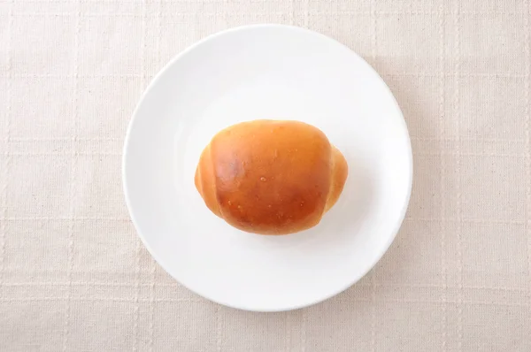 Rolo de pão de manteiga em um prato na toalha de mesa — Fotografia de Stock
