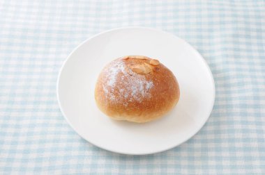 masa örtüsü üzerinde bir tabak üzerinde tereyağı ekmek rulo