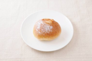 masa örtüsü üzerinde bir tabak üzerinde tereyağı ekmek rulo