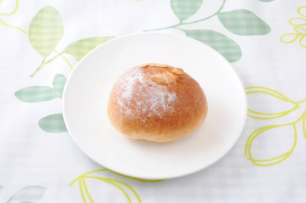 Rolo de pão de manteiga em um prato na toalha de mesa — Fotografia de Stock