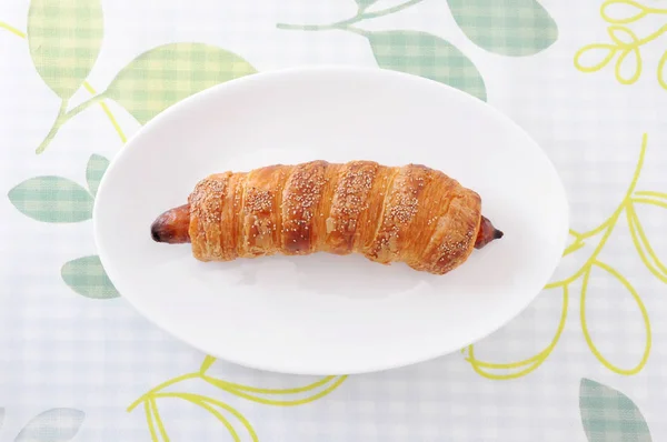 Sausage roll bread on plate on table cloth — Stock Photo, Image