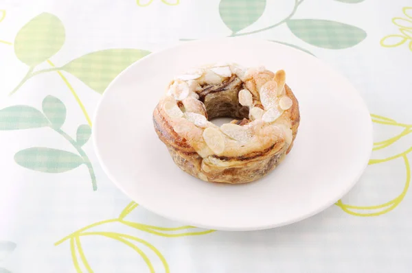 Sweet almond cake doughnut on a plate table cloth — Stock Photo, Image