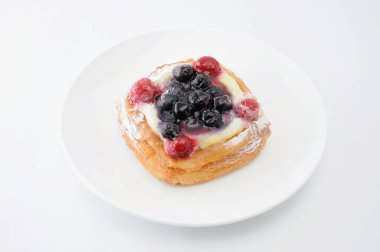 beyaz arka plan üzerinde bir tabak üzerinde muhallebi krema ile yaban mersini kek