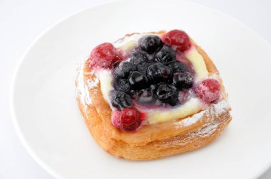 beyaz arka plan üzerinde bir tabak üzerinde muhallebi krema ile yaban mersini kek